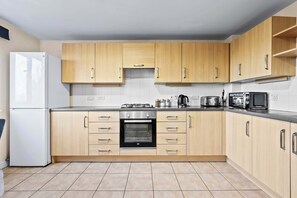 Eine Küche mit Holzausstattung, integriertem Backofen, Kühlschrank und Mikrowelle.