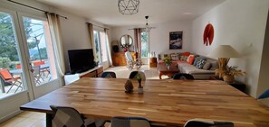 Ein geräumiger Wohnbereich mit großem Holzesstisch, einer Couch und einem Fernseher.