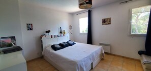 Ein Schlafzimmer mit einem Bett, einem Heizkörper, einem Fenster und einer Wanduhr.