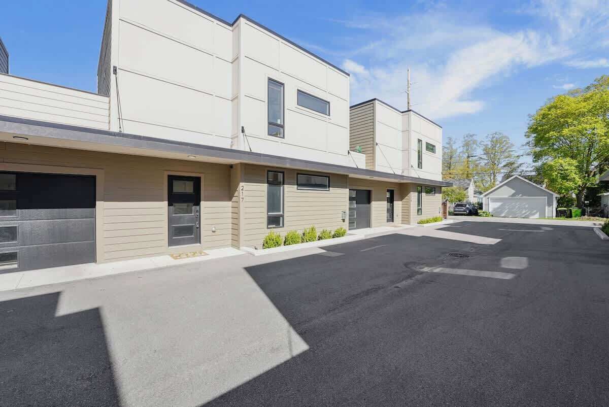 A modern multi-story building with a flat roof, large windows, and a parking lot.