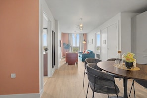 A modern living room with a dining area, a sofa, and a view through a large window. - GuestReady - Chic 2-Bed Apartment with Balcony (Manchester)