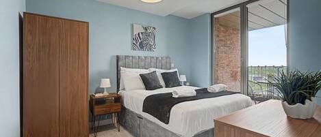 A bedroom with a bed, bedside tables, a wardrobe, a balcony with a view, and a hanging light fixture.