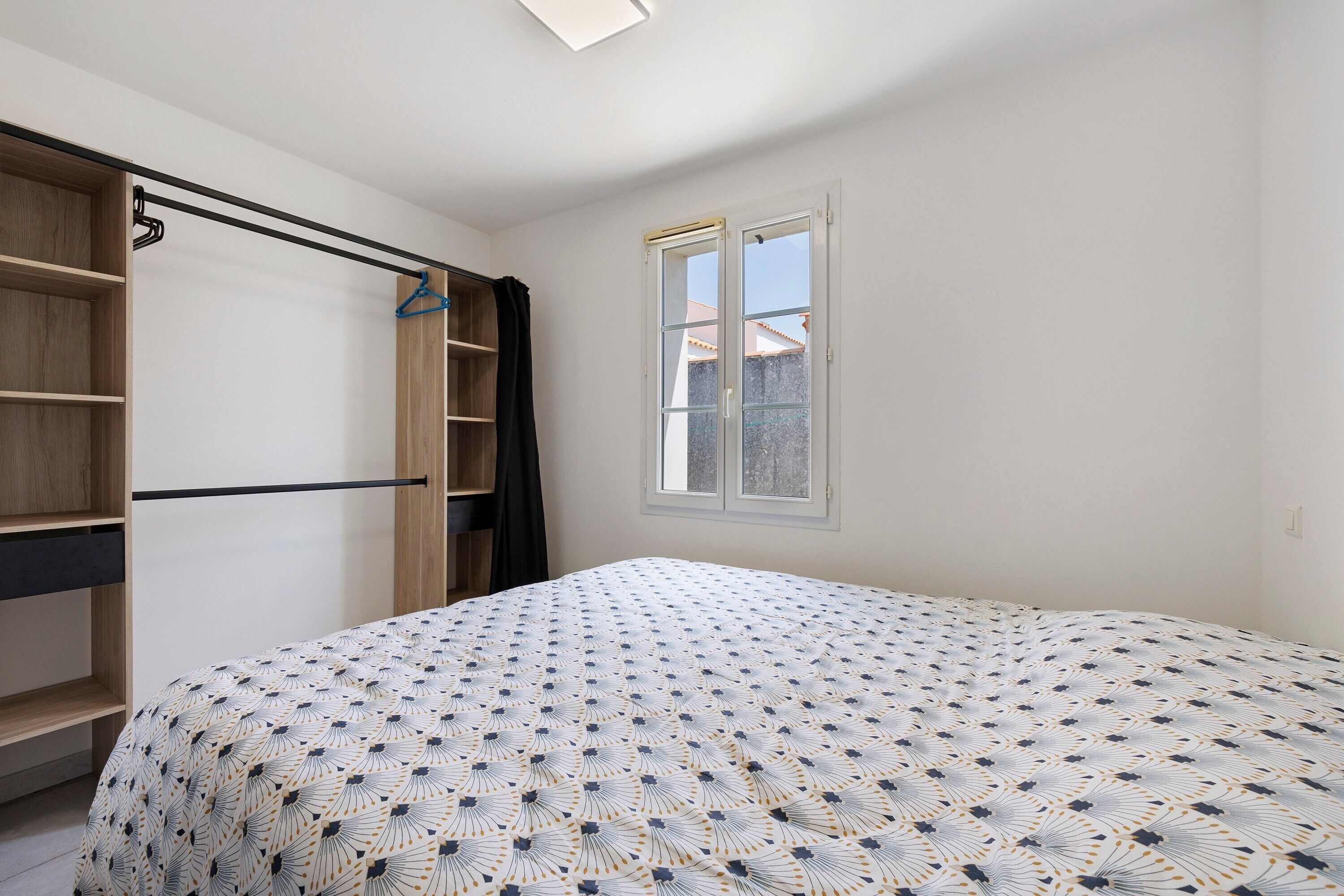 Ein Schlafzimmer mit Bett, Kleiderschrank, Fenster und Tür.