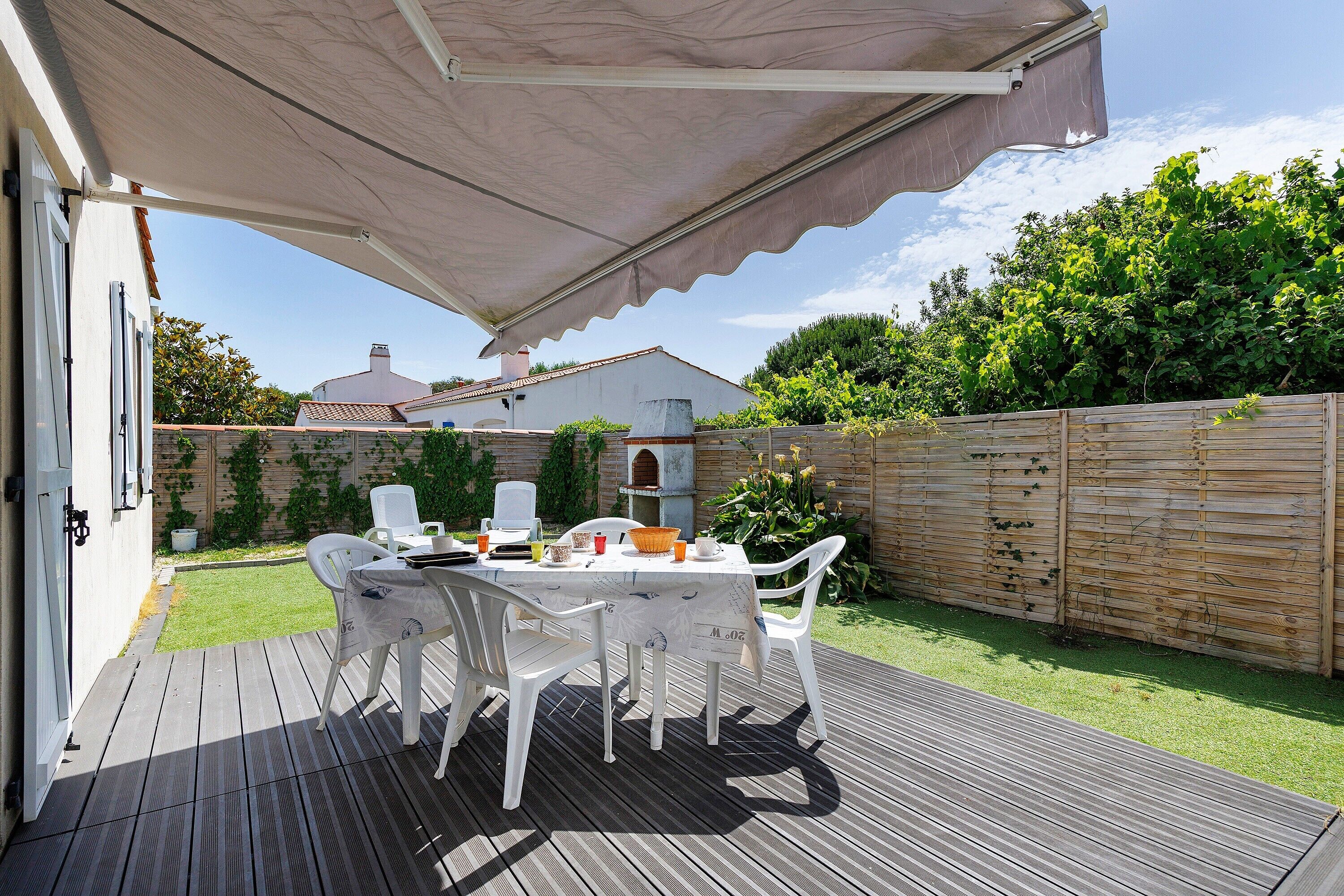 Un portico coperto con tavolo e sedie, un'area con decking in legno e un giardino.