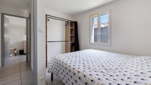 Um quarto com uma cama, um guarda-roupa, uma janela e uma porta que dá para um banheiro.