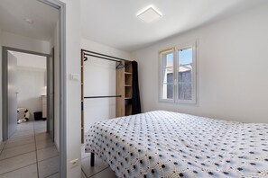 Ein Schlafzimmer mit Bett, Kleiderschrank, Fenster und einer Tür zu einem Badezimmer.