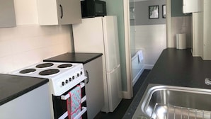 A compact kitchen with a stove, refrigerator, and a sink. - Stylish 2BR House in Coventry - Ideal for Business and Groups (West Midlands)
