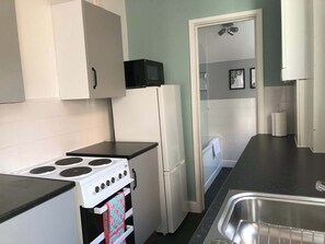Eine kleine Küche mit Herd, Kühlschrank und Spüle.