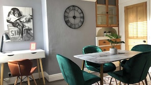 A dining area with a marble table, green velvet chairs, a clock, and a cabinet with glass doors. - Stylish 2BR House in Coventry - Ideal for Business and Groups (West Midlands)
