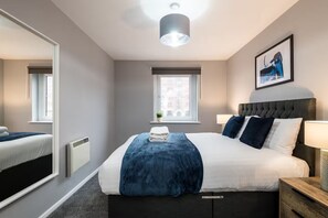 A modern hotel room with a large bed, bedside lamps, a window, and a mirror. - GuestReady - Chic 2bed with Balcony in Liverpool (Liverpool)