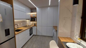 Eine kompakte Küche mit Kühlschrank, Mikrowelle, Backofen und Spüle.