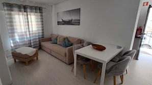 Ein Wohnbereich mit Sofa, Hocker und einem Esstisch mit Stühlen.