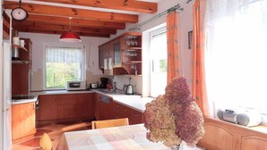 Una cucina con travi in legno, un tavolo da pranzo con un vaso di fiori e una finestra con tende.