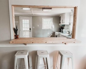 A kitchen with a wooden countertop, white cabinets, a window, and a potted plant.