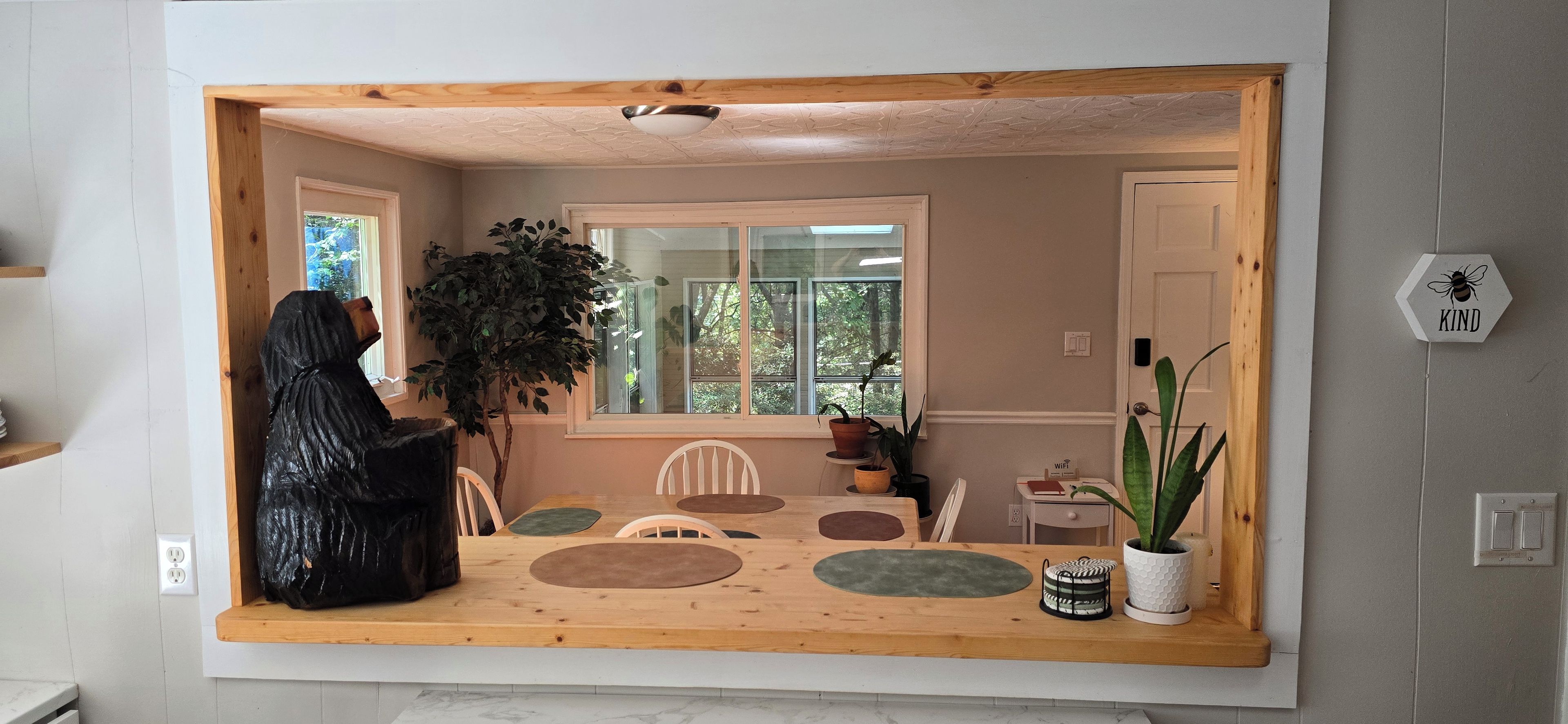 Een eethoek met een houten tafel, stoelen en een plant in een pot.