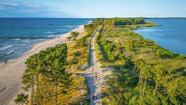 Ein Küstenpfad mit Strand und bewaldeten Gebieten.