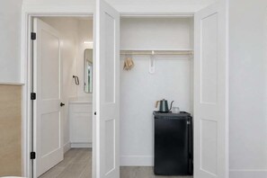 A compact room with a white door, a small black refrigerator, a mirror, and a towel rack. - Bishop Arts 6BD/6BA Townhouse, Parking, Sleeps 12 (Dallas)