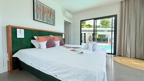 Une chambre d’hôtel avec un grand lit, une vue sur la piscine et une porte-fenêtre coulissante.