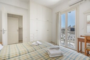 Ein Schlafzimmer mit Bett, Kleiderschrank, einem Balkon mit Blick und einem kleinen Tisch.