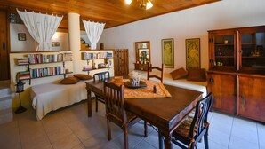 A cozy living room with a wooden ceiling, a dining table, bookshelves, a sofa, and a cabinet. - Villa 'Apartment 2' with Private Terrace (Archanes)