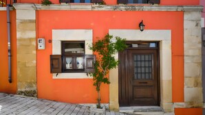 A building with a wooden door, a small window with shutters, and a wall-mounted light fixture. - Villa 'Apartment 2' with Private Terrace (Archanes)