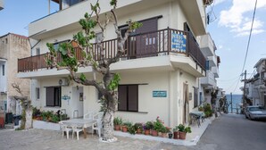 Un edificio de dos pisos con balcones, plantas en macetas y mesas al aire libre.