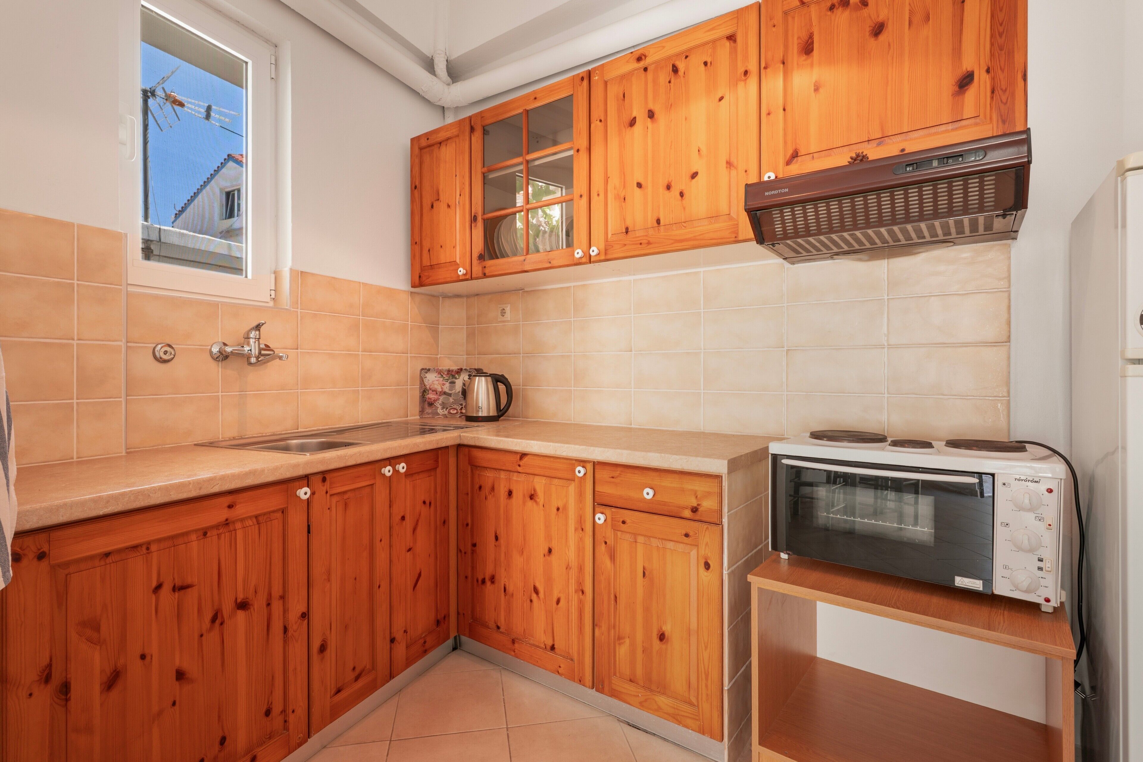 A kitchen with wooden cabinets, a microwave, and a window with a view of a building.