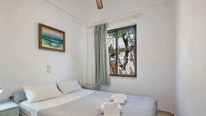 Un dormitorio con cama, mesita de noche, lámpara, ventana con cortinas y un cuadro en la pared.