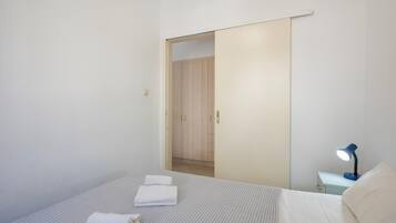Een slaapkamer met een bed, nachtkastje, bureaulamp en een kledingkast.