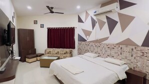 Une chambre d’hôtel équipée d’un lit, d’un canapé, d’une télévision, d’une armoire et d’un ventilateur de plafond.