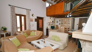 A living room with two sofas, a coffee table, and a fireplace. There is a staircase leading to an upper level.