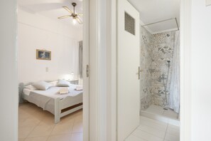 Ein Schlafzimmer mit einem Bett, einem Nachttisch und einer Dusche mit gemusterten Fliesen.