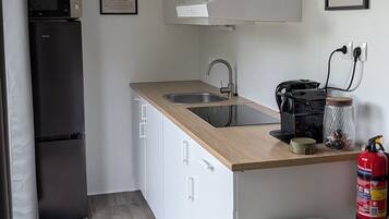 A compact kitchen with a sink, a microwave, a refrigerator, and a coffee machine.