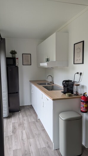 A compact kitchen with a sink, a microwave, a refrigerator, and a coffee machine. - Cube 24 | 4 persoons chalet in Zennewijnen (Zennewijnen)