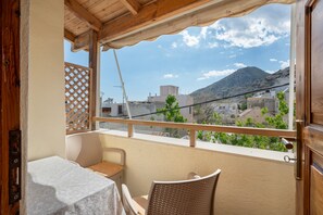 Ein Balkon mit Tisch und Stühlen, Holzboden und Blick auf Gebäude sowie einen Berg.