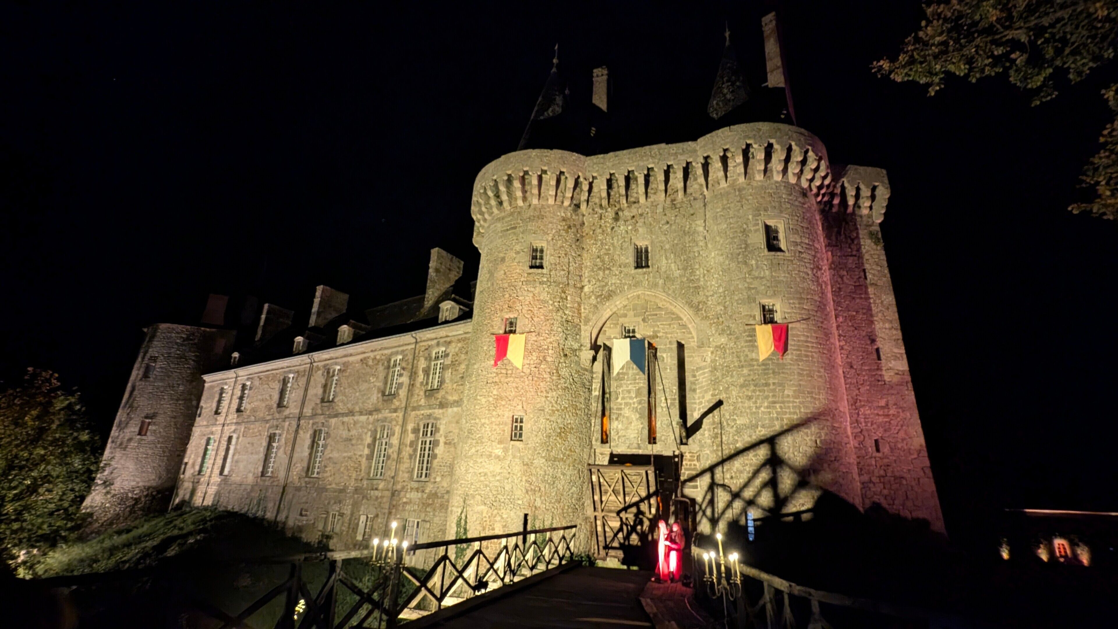 Un château historique doté d’une grande tour centrale, d’une entrée principale et d’un pont menant au château.