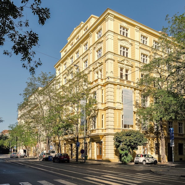 Ein mehrstöckiges Gebäude mit klassischer Architektur, eine Straße davor und geparkte Autos.