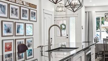 A modern kitchen with a glass backsplash, stainless steel appliances, and a 'OUR BRAG WALL' above the sink.