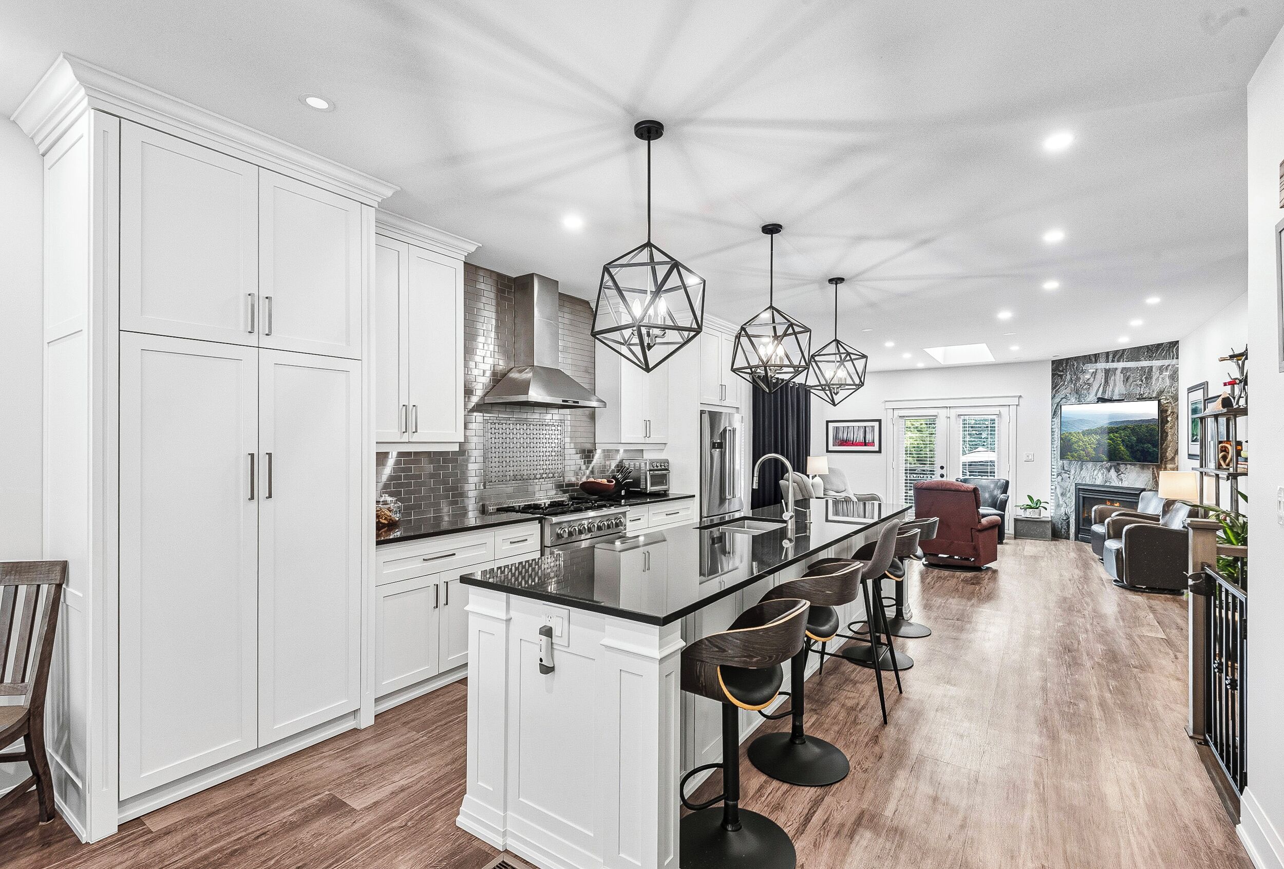 A modern kitchen with white cabinetry, a central island with bar stools, and pendant lighting.