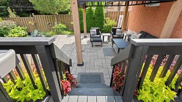 En træterrasse med pergola, udendørs møbler og en murstensvæg.