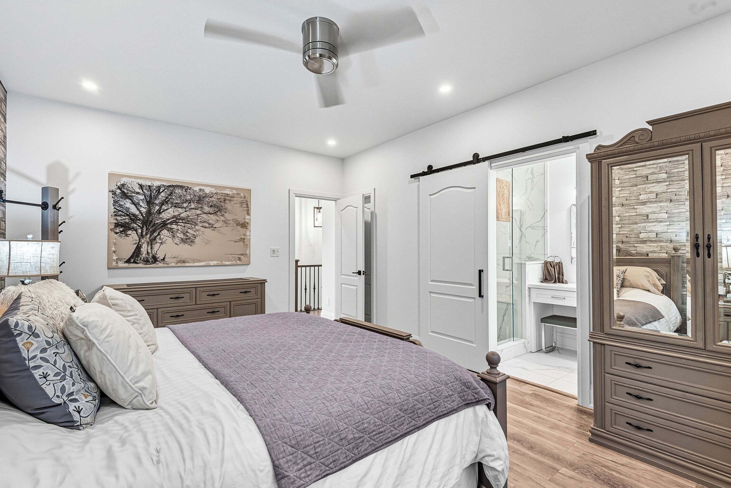 A bedroom with a bed, a wardrobe, a desk, and a painting on the wall.