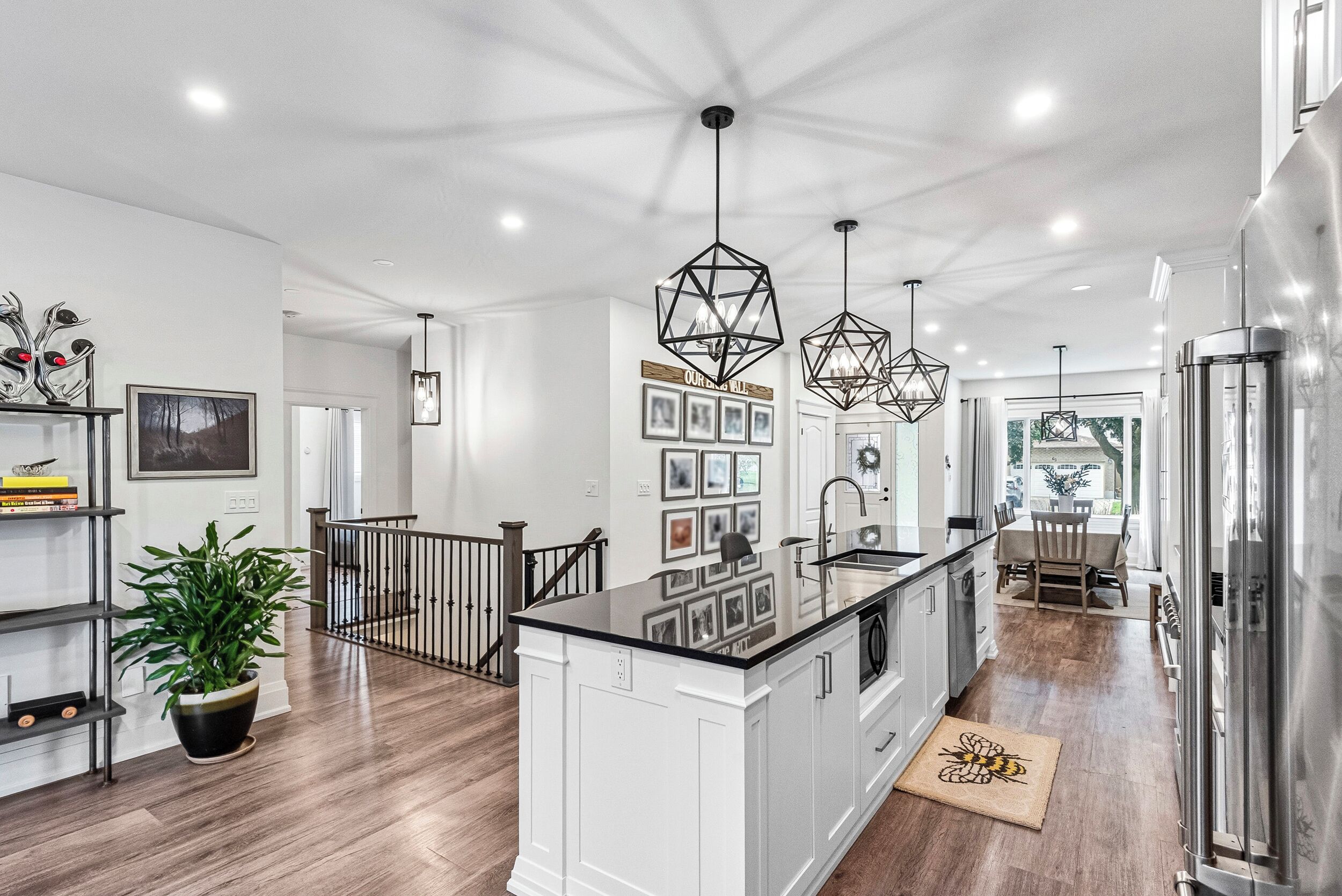 A modern kitchen with a central island, pendant lights, and a staircase leading to another level.