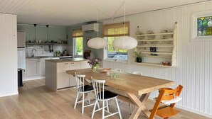 Una cocina con armarios blancos, una mesa de comedor de madera y una lámpara colgante.