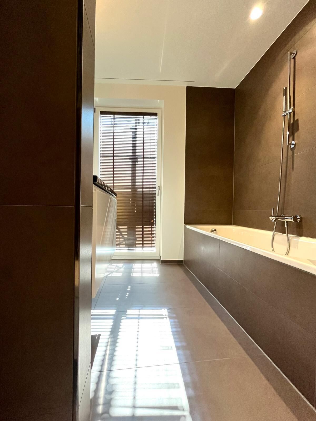 Un baño moderno con bañera, ducha y puerta que da a una escalera.