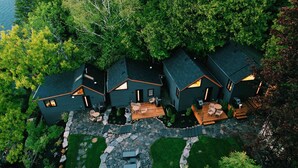 A modern house with a stone patio, outdoor seating, and a well-maintained lawn. - Away Cabins (Roseneath)