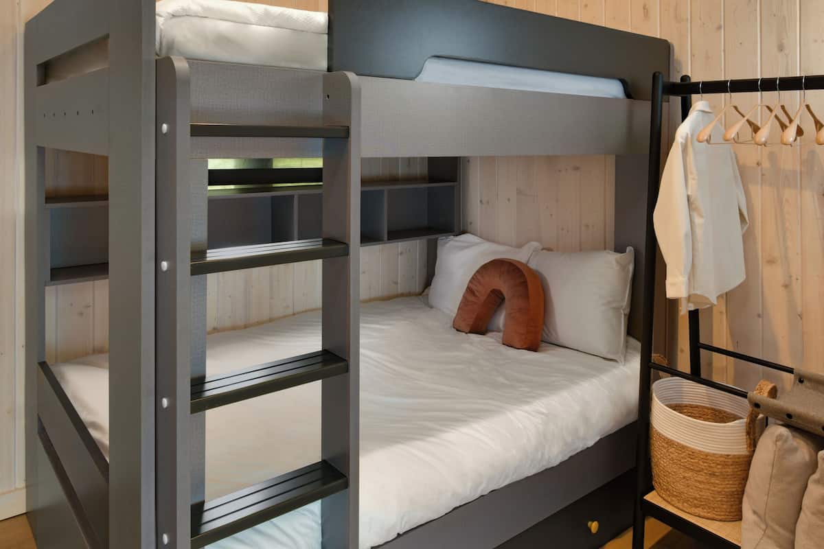 A bunk bed with a headboard, a bedside table, and a hanging rack with clothes.
