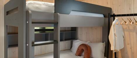 A bunk bed with a headboard, a bedside table, and a hanging rack with clothes.