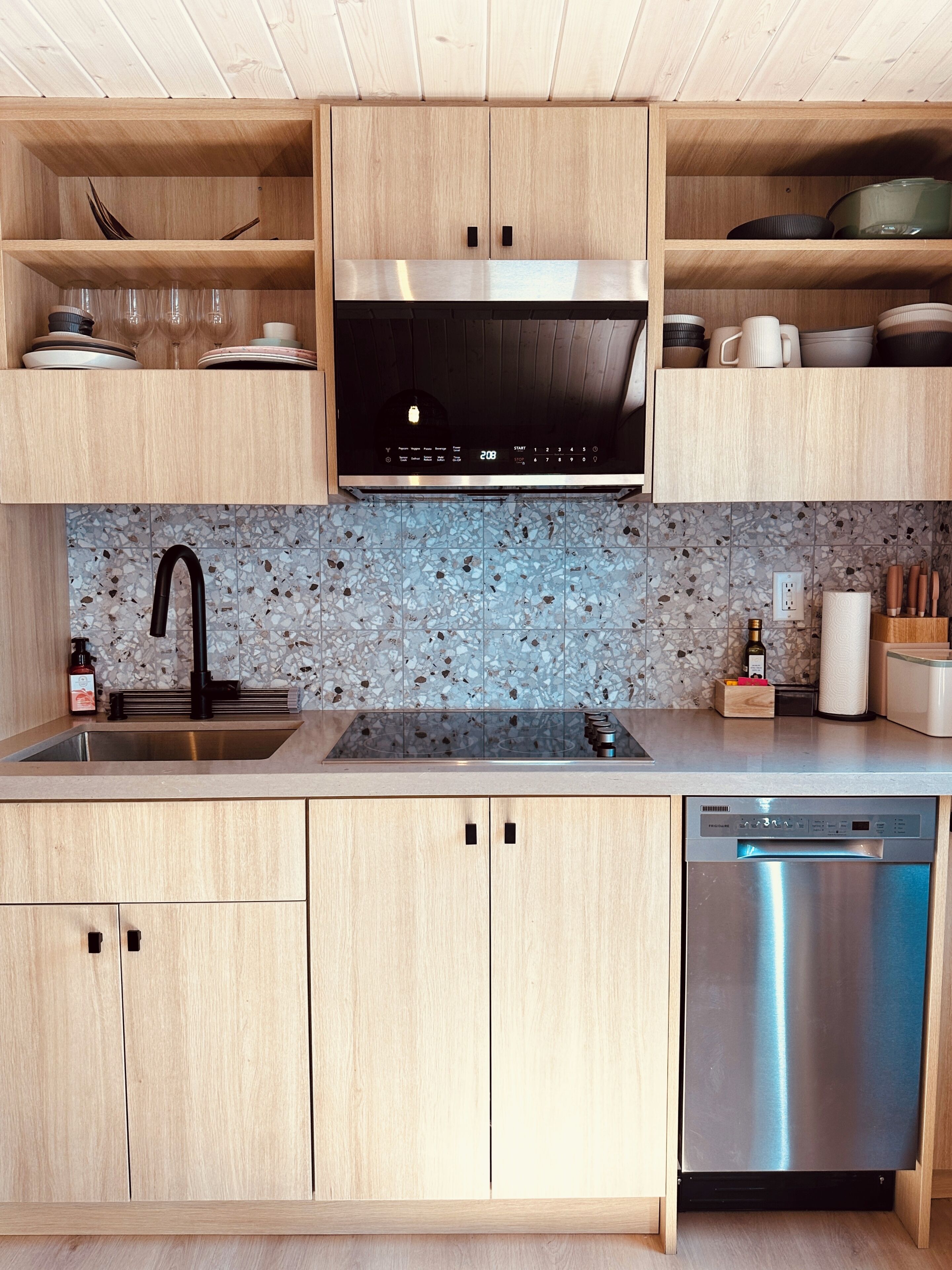 Una cucina moderna con mobili in legno, lavastoviglie in acciaio inossidabile e piano di lavoro in granito.