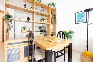 Ein Essbereich mit einem Holztisch, Stühlen und einer Einbauschränke mit Pflanzen.