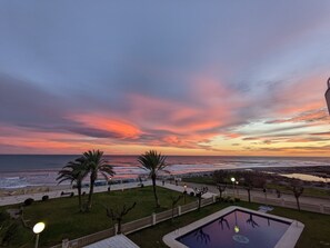 Ein Poolbereich mit Blick auf das Meer und den Sonnenuntergang.